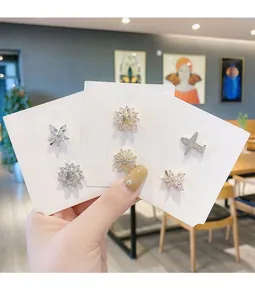 Detailansicht von Mini-Zirkonia-Blumen- und Flugzeug-Broschen auf weißen Schmuckkarten