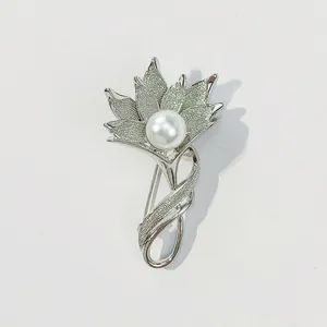 Detaillierte Makroansicht einer silbernen Blumenbrosche mit einer eleganten weißen Perle