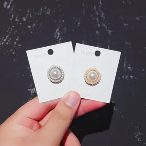 Detail van elegante magnetische parelbrosches op witte displaykaarten voor zijden overhemden