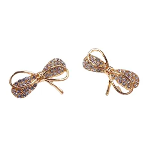 Coppia di eleganti spille a forma di fiocco dorato con cristalli per abbigliamento.