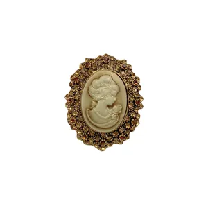 Broche camée de style victorien vintage avec strass ambrés sur fond blanc.