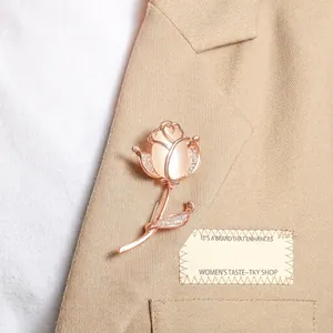 Elegant rose gold flower brooch with opal stone and rhinestones on khaki blazer fabric.