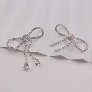 Detail showing the intricate rhinestone bow design and elegant crystal tassel drops on brooch