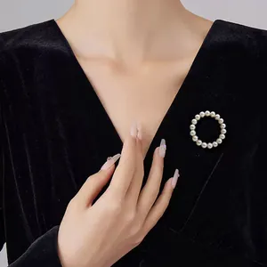 Detailaufnahme einer runden Perlenbrosche an einem eleganten schwarzen Samtkleid