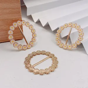 Detailansicht von goldenen Gänseblümchen-Kleiderschnallen und strukturierten Schalringen
