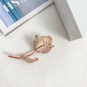 Elegant rose gold flower brooch with cat-eye stone and rhinestones on a white background.