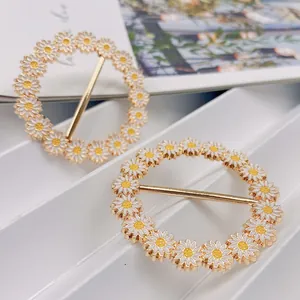 Detailansicht von zwei goldfarbenen Gänseblümchen-Knotenschnallen für Hemden und T-Shirts.