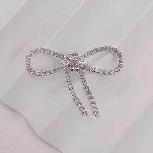 Detailed view of silver bow brooch with sparkling rhinestones and elegant tassels