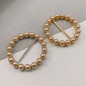 Detailansicht von runden Schalschnallen in Gold und Silber mit eleganten Pfirsichperlen