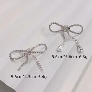 Detailed view of silver rhinestone bow brooches with sparkling tassel and teardrop pendants.