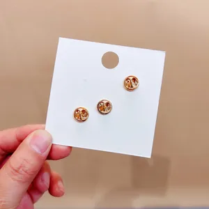 Detailansicht von drei goldfarbenen Metall-Schmetterlingsverschlüssen auf weißer Karte.