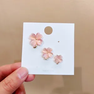 Set mit drei eleganten rosa Katzenaugen-Kleeblatt-Anstecknadeln auf einer weißen Karte
