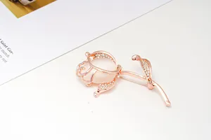 Close-up of elegant rose brooch with white stone and rhinestones in rose gold finish.