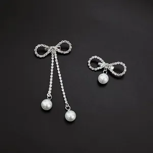 Elegant silver bow brooch with rhinestone tassels and pearls on a black background