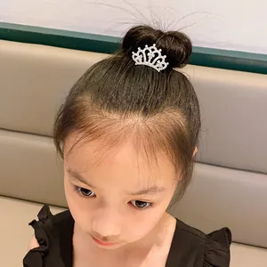 Detail shot of a sparkling silver rhinestone crown hair comb worn on a young girl's bun.