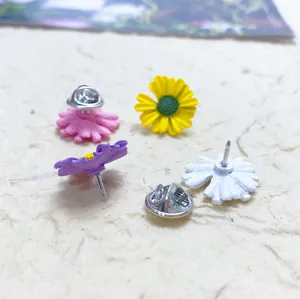 Close-up of colorful daisy enamel pins showing front petals and back butterfly clutch.