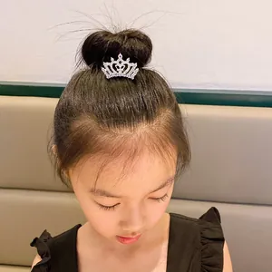 Detailed view of a child wearing a sparkling rhinestone crown hair comb on top bun