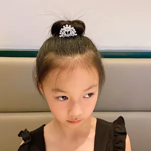 Detail view of a sparkling rhinestone crown hair comb on a young girl's hair bun.