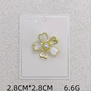 Detailansicht einer goldfarbenen Blumenbrosche mit Perlmuttblüten und Perlen auf Karte