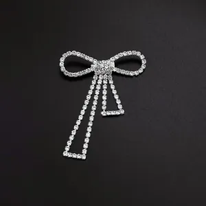 Detailed macro view of a sparkling silver-tone rhinestone bow brooch with hanging tassels