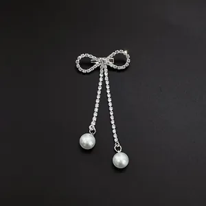 Elegant silver bow brooch featuring sparkling rhinestone tassels and white dangling pearls
