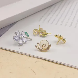 Nahaufnahme eleganter Blumen- und Schnecken-Anstecknadeln mit Zirkon-Details