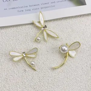 Detailansicht von drei eleganten goldenen Libellen-Broschen mit Perlen und Muschelflügeln