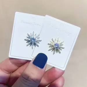 Detailansicht eleganter Kupfer-Zirkonia-Sonnenstrahl-Broschen auf weißen Displaykarten