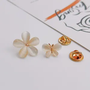 Macro detail of cat eye stone flower and butterfly brooches with elegant gold backings.