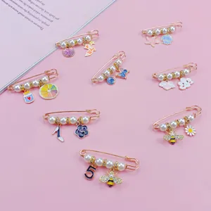 Primo piano di spille decorative con perle e ciondoli colorati su sfondo rosa