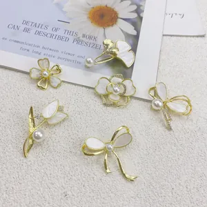 Detailansicht goldener Muschel-Broschen mit Perlen in Blumen- und Schleifenform