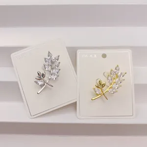 Detailansicht eleganter Blattbroschen in Gold und Silber mit funkelnden Zirkonia