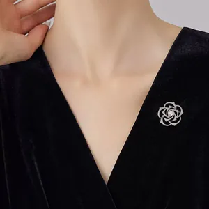 Close-up of elegant camellia brooch with pavé crystals and pearl on black velvet dress