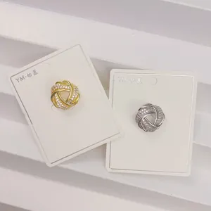 Detailaufnahme von geknoteten Kupferbroschen mit funkelndem Zirkonia auf Displaykarten.