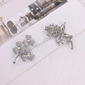 Detailed view of elegant silver-toned brooch with sparkling rhinestones and clover design