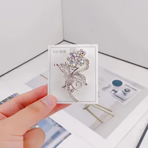 Close-up view of an elegant silver floral brooch with sparkling rhinestones on a card.