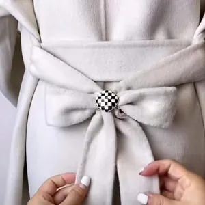 Vue détaillée d'une boucle émaillée à damier noir et blanc sur une ceinture de manteau