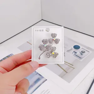 Close-up macro shot of an elegant silver clover brooch adorned with sparkling clear rhinestones