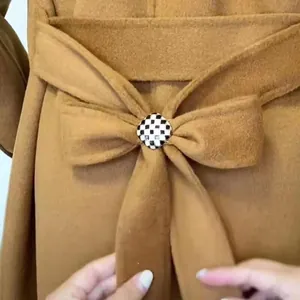 Détail macro d'une boucle de foulard en émail à damier noir et blanc sur du tissu.