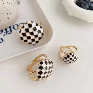 Détail de la boucle de foulard en émail à motif damier noir et blanc sur support doré
