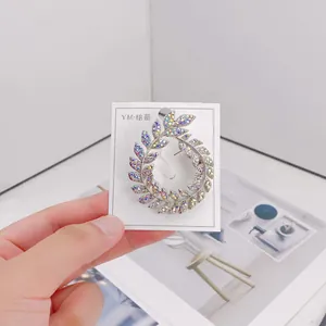 Macro view of an elegant silver wreath brooch with iridescent rhinestones on card
