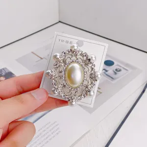 Detailed view of an elegant vintage pearl and rhinestone brooch pinned to a white card