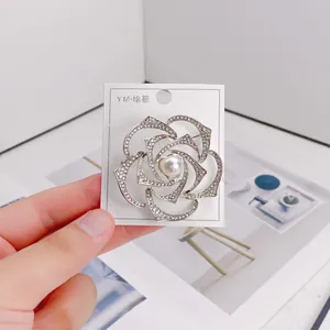 Detailed macro shot of an elegant silver rose brooch with sparkling rhinestones and pearl