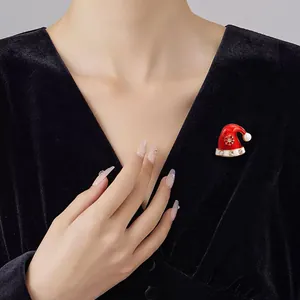 Nahaufnahme einer festlichen roten Weihnachtsmann-Hut-Brosche an einem schwarzen Samtkleid