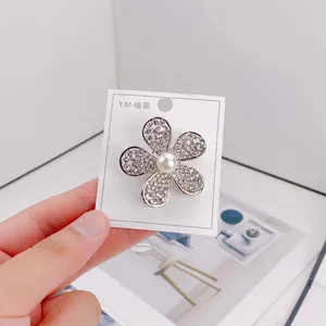 Detail of elegant five-petal flower brooch featuring sparkling rhinestones and a pearl center.