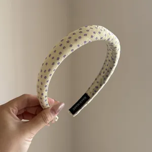 Close-up detail of yellow fabric padded headband featuring a delicate purple floral pattern