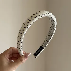 Detailed view of a white floral fabric headband featuring a handmade tag detail.