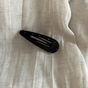 Close-up of a black corduroy triangle hair clip with white polka dots on fabric