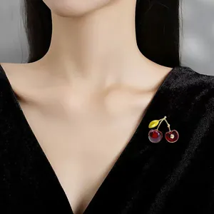Detailed macro shot of an elegant red cherry brooch pinned on a black velvet dress