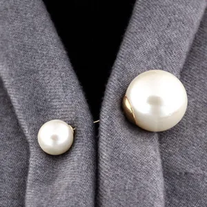 Detailansicht einer eleganten Doppelperlen-Brosche auf grauer Strickkleidung befestigt